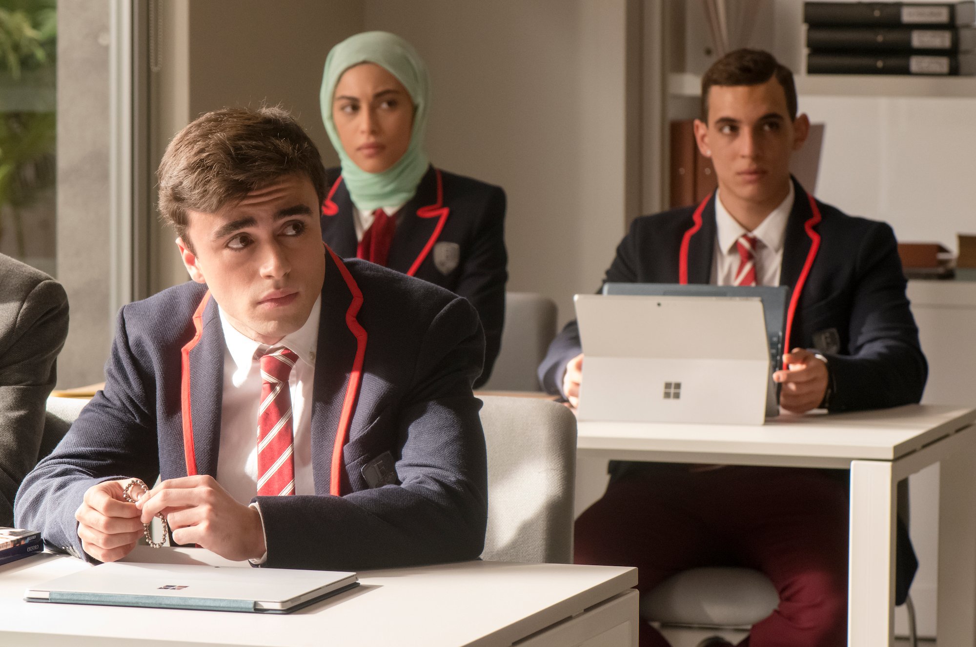 Itzan Escamilla, Mina El Hammani, Miguel Herran sitting in a classroom in 'Elite' Season 1.