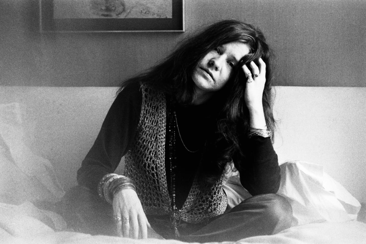 Janis Joplin sits and stares unsmiling at the camera.