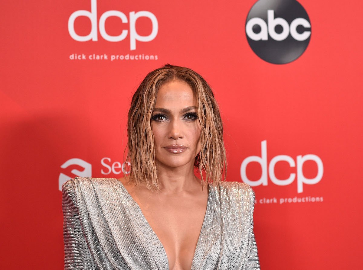 Jennifer Lopez smiling in front of a red background