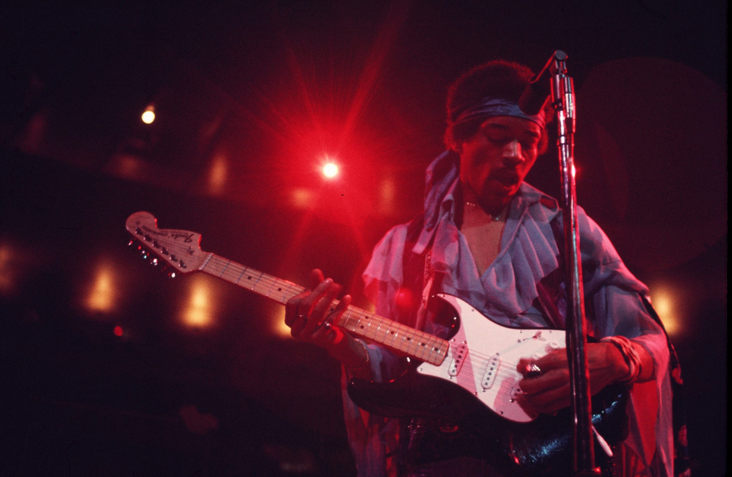 Jimi Hendrix plays guitar on stage.