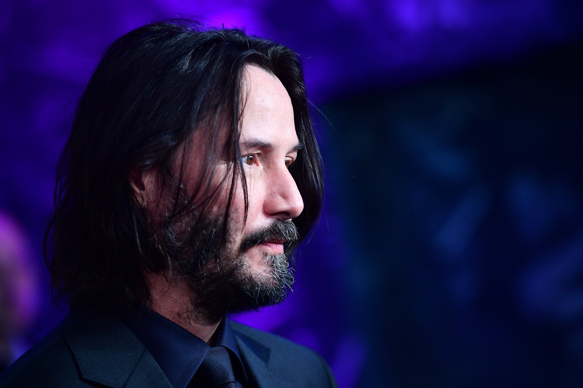 'John Wick 4' actor Keanu Reeves from the side in front of a purple background at the 'John Wick: Chapter 3 - Parabellum' Special Screening