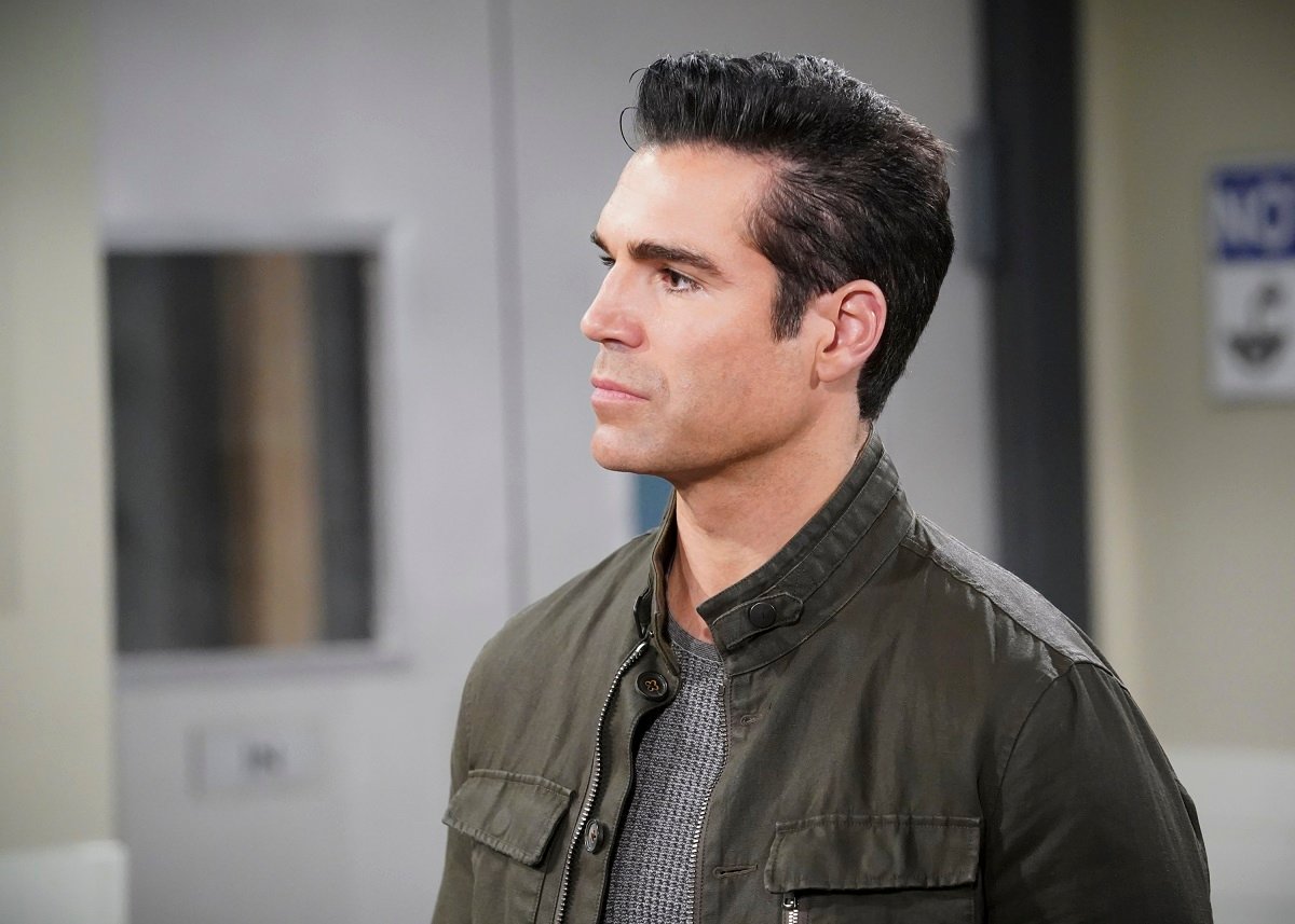 'The Young and the Restless' actor Jordi Vilasuso wearing a grey shirt and jacket, and standing in a hospital set.