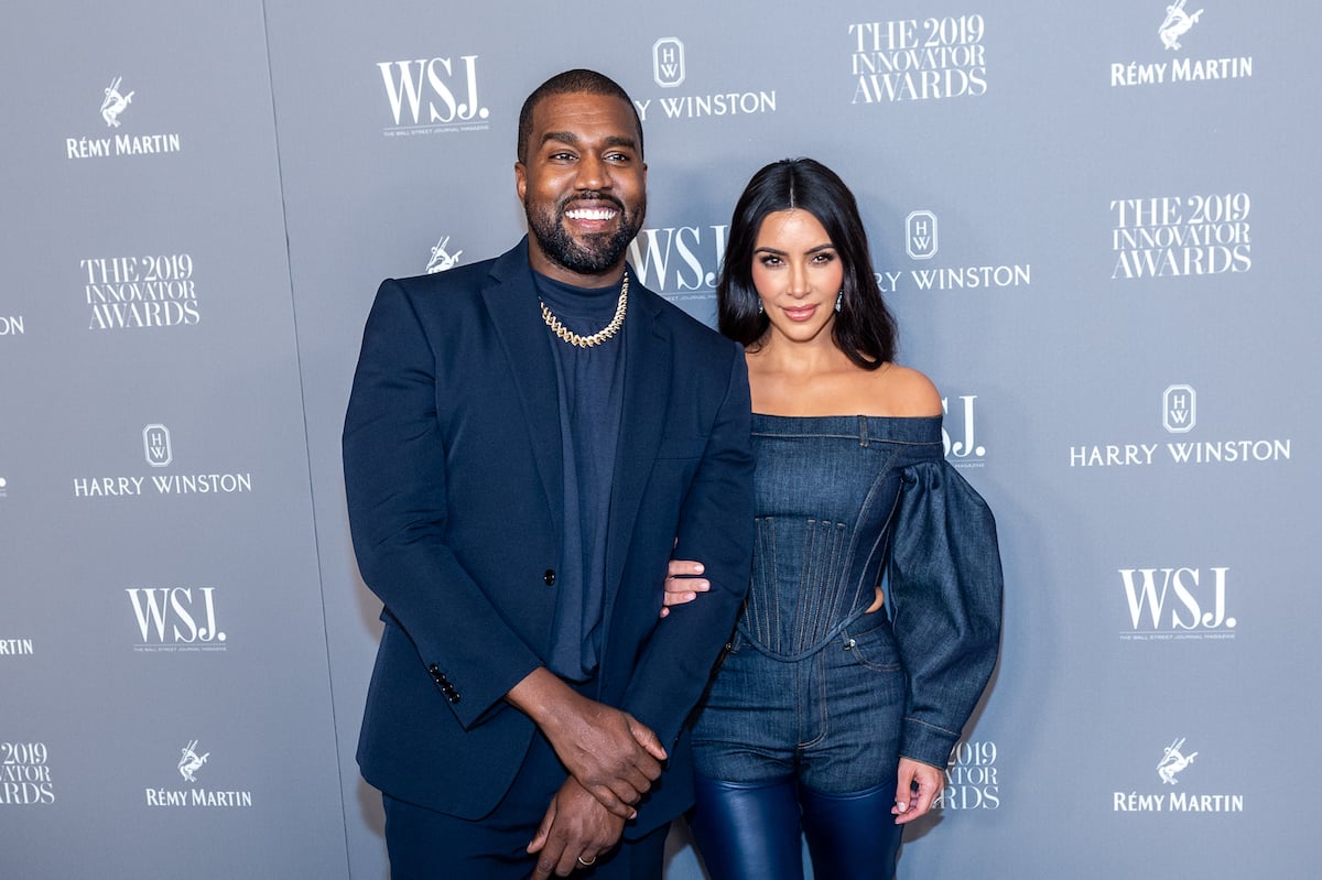 Kanye West and Kim Kardashian West pose together at an event in matching blue outfits.