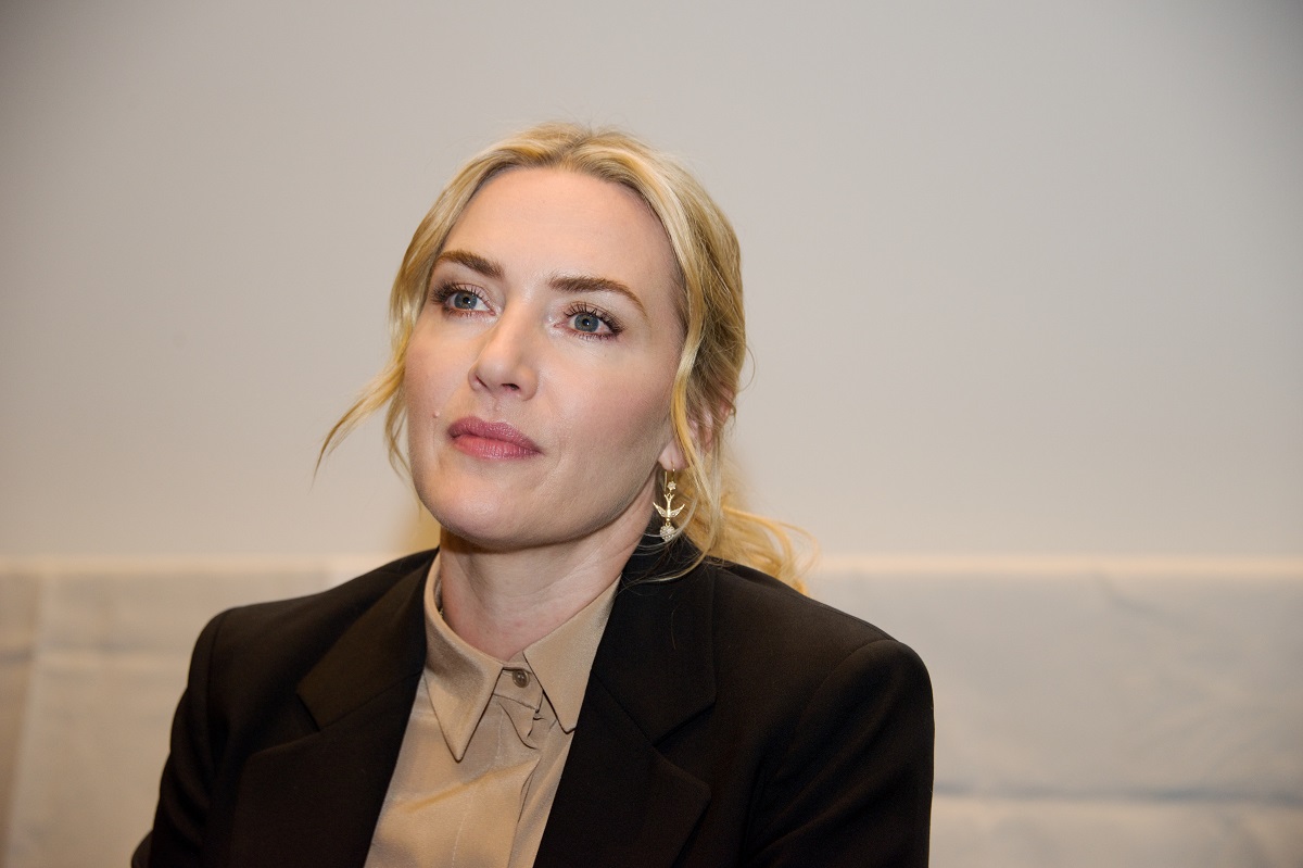Kate Winslet wearing a business suit while sitting down