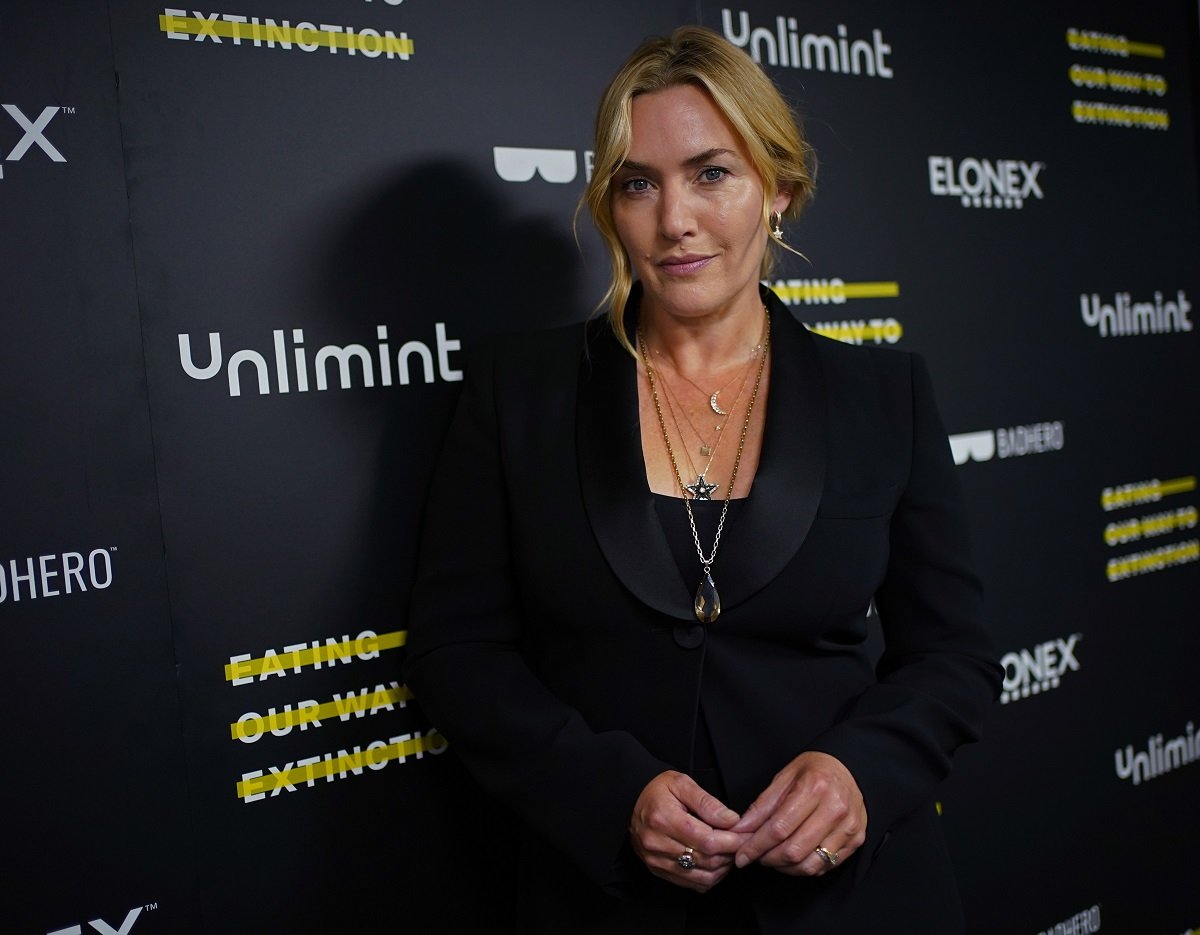 Kate Winslet posing while wearing a necklace and a black suit