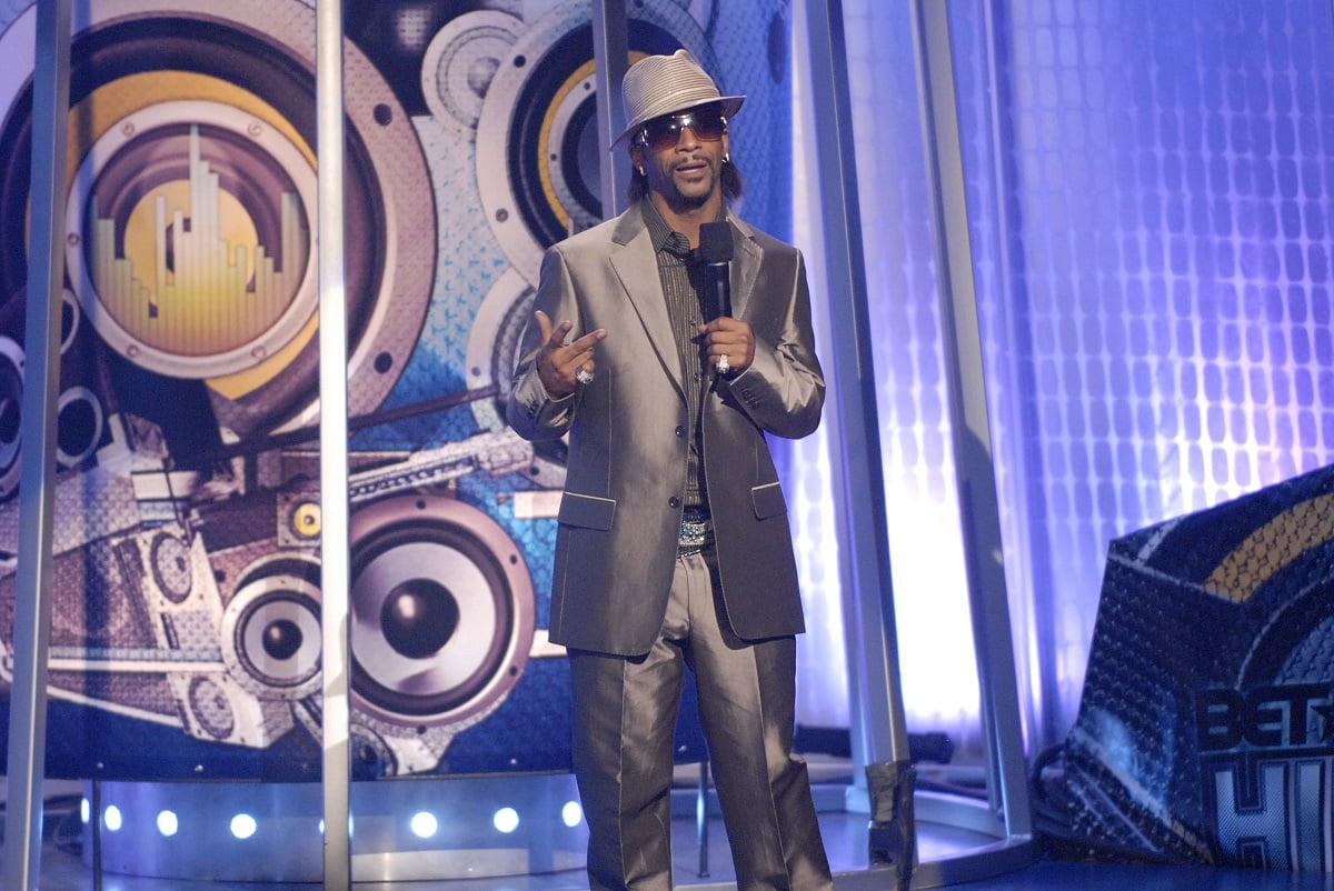 Katt Williams in a silver suit speaking on stage