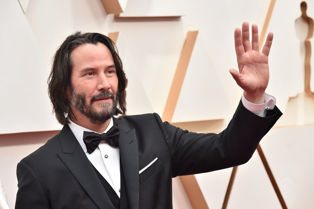 Keanu Reeves waving in a suit