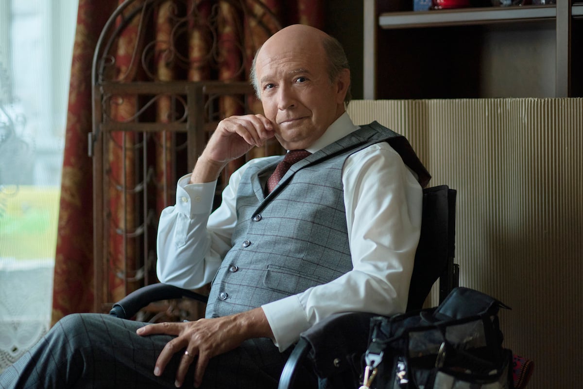 Keith Dinicol, wearing a vest and sitting in a chair, in an episode of 'Chesapeake Shores' Season 5