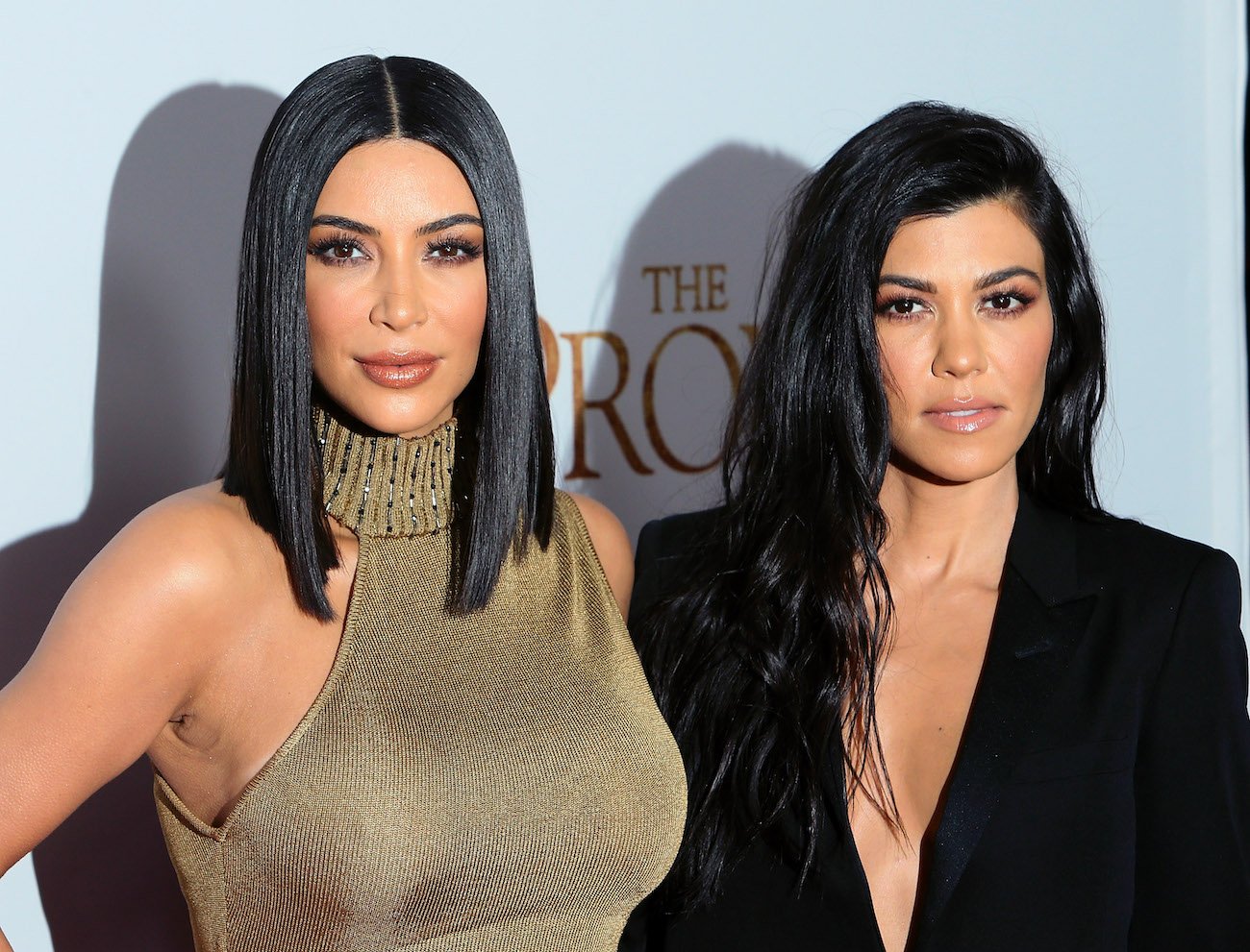 Kim Kardashian and Kourtney Kardashian standing next to each other