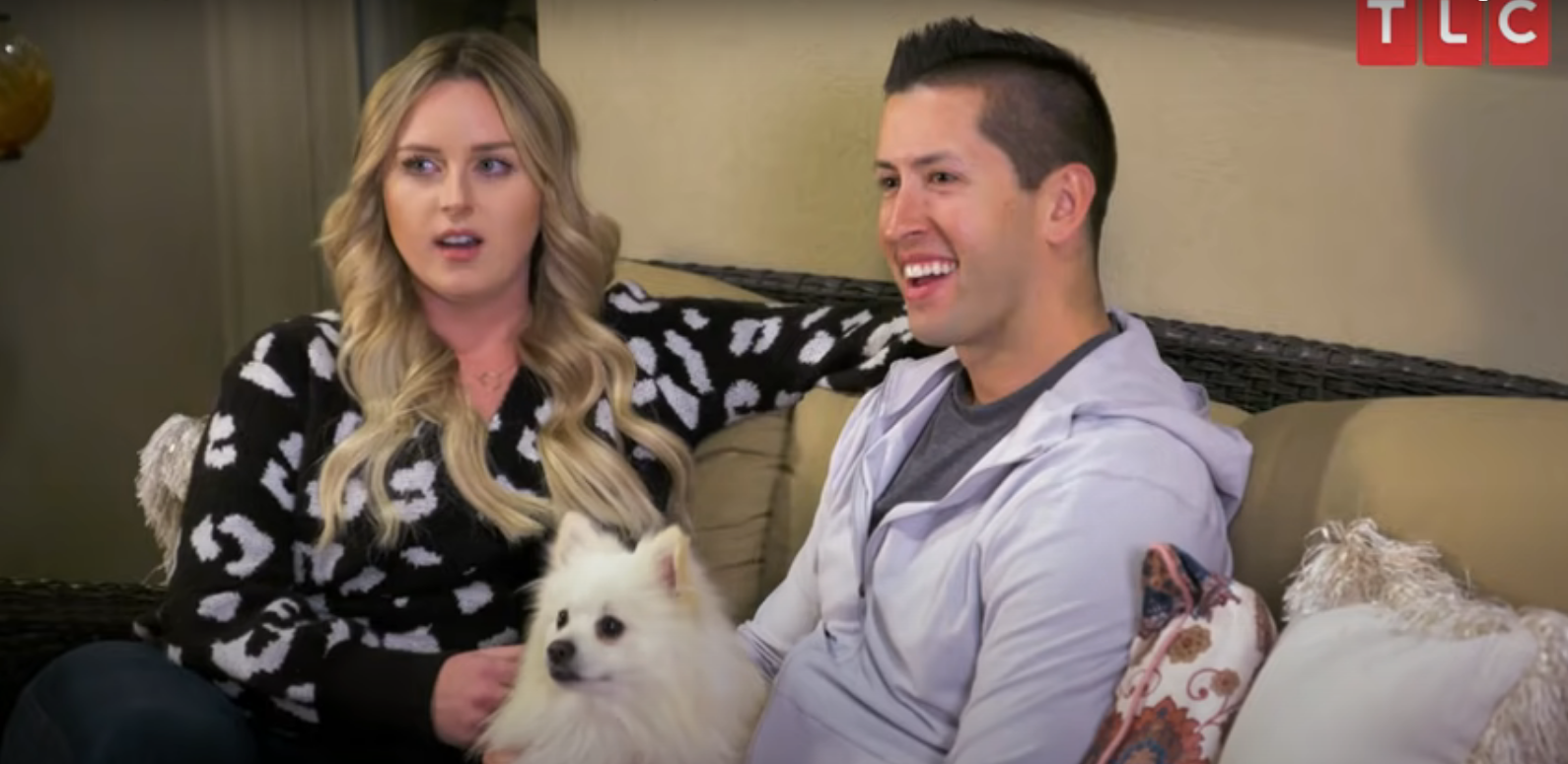 Kim and Matt sitting on a couch with a white dog in 'I Love a Mama's Boy'