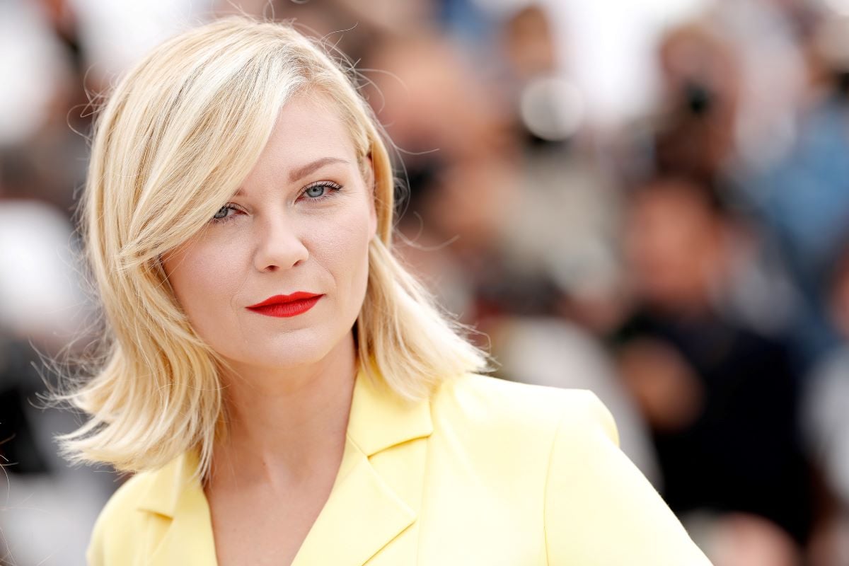 Kirsten Dunst in a yellow shirt, with short blond hair and red lipstick