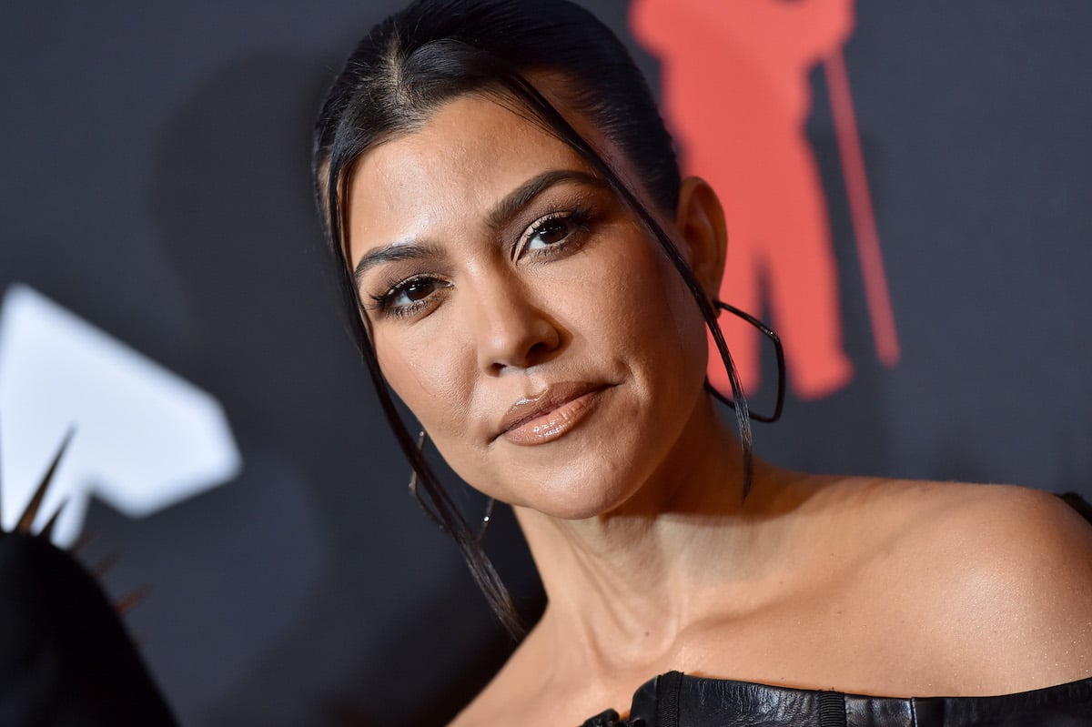 Kourtney Kardashian smiling in front of a black background