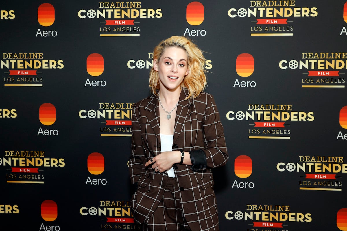 Kristen Stewart smiling in front of a dark backdrop