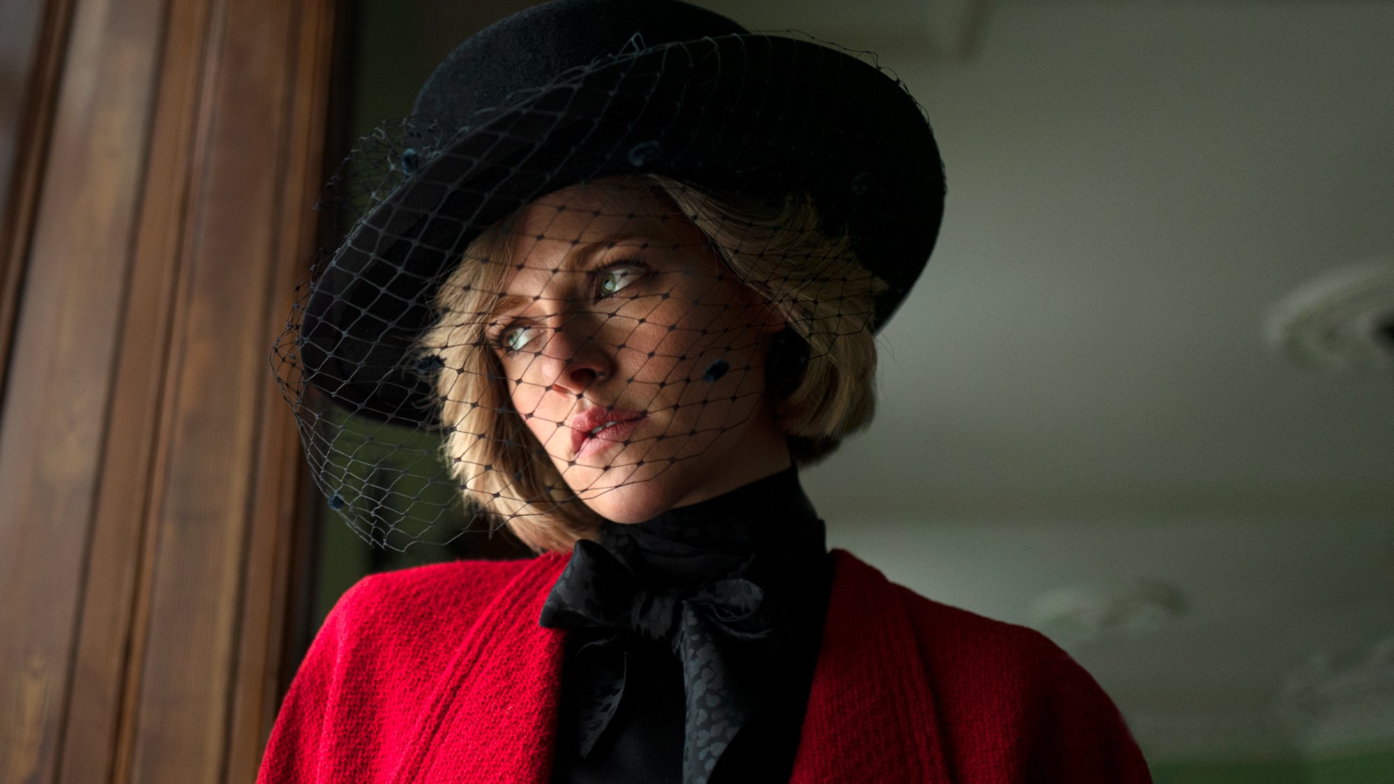 Kristen Stewart as Princess Diana in 'Spencer' looking out the window with a black veil covering her face.