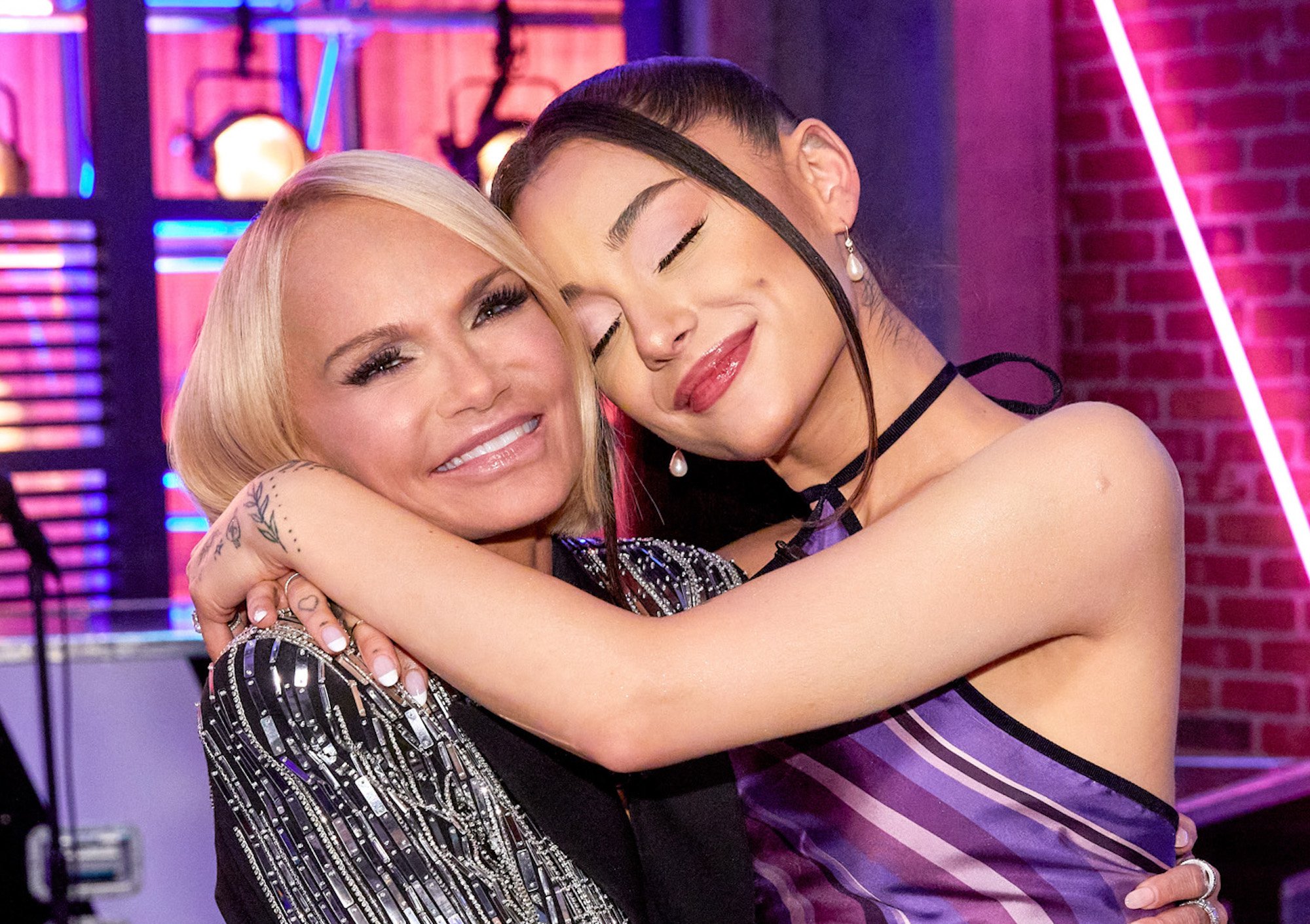 Kristin Chenoweth and Ariana Grande on set of 'The Voice.' The women hug and smile for the camera on set of the singing competition.