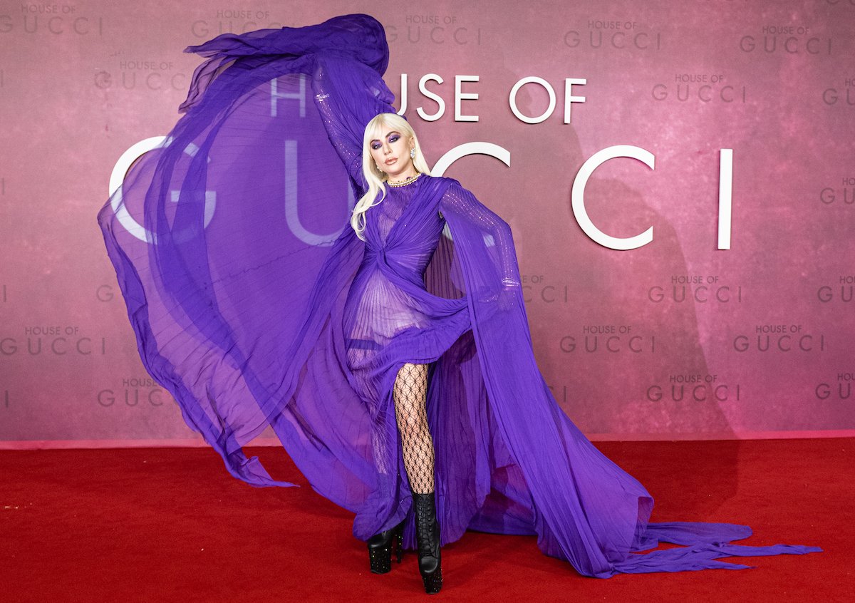 Lady Gaga in front of a pink background wearing a purple dress