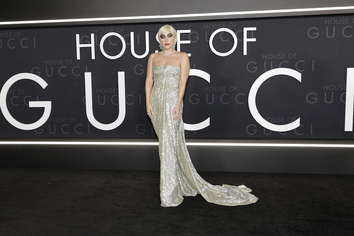 Lady Gaga stand before a "House of Gucci" sign.