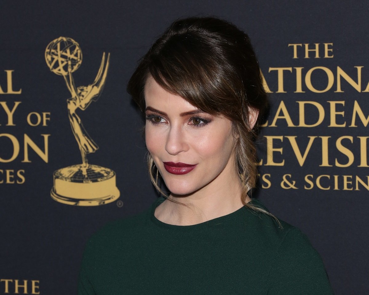 'The Bold and the Beautiful' actor Linsey Godfrey wearing a green dress and dark red lipstick; poses on the Emmys red carpet.
