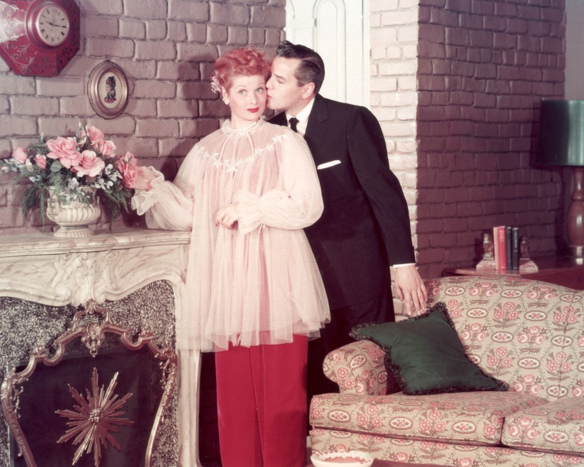 Lucille Ball receives a kiss on the cheek from her husband, musician Desi Arnaz, on the set of their television series, 'I Love Lucy'.