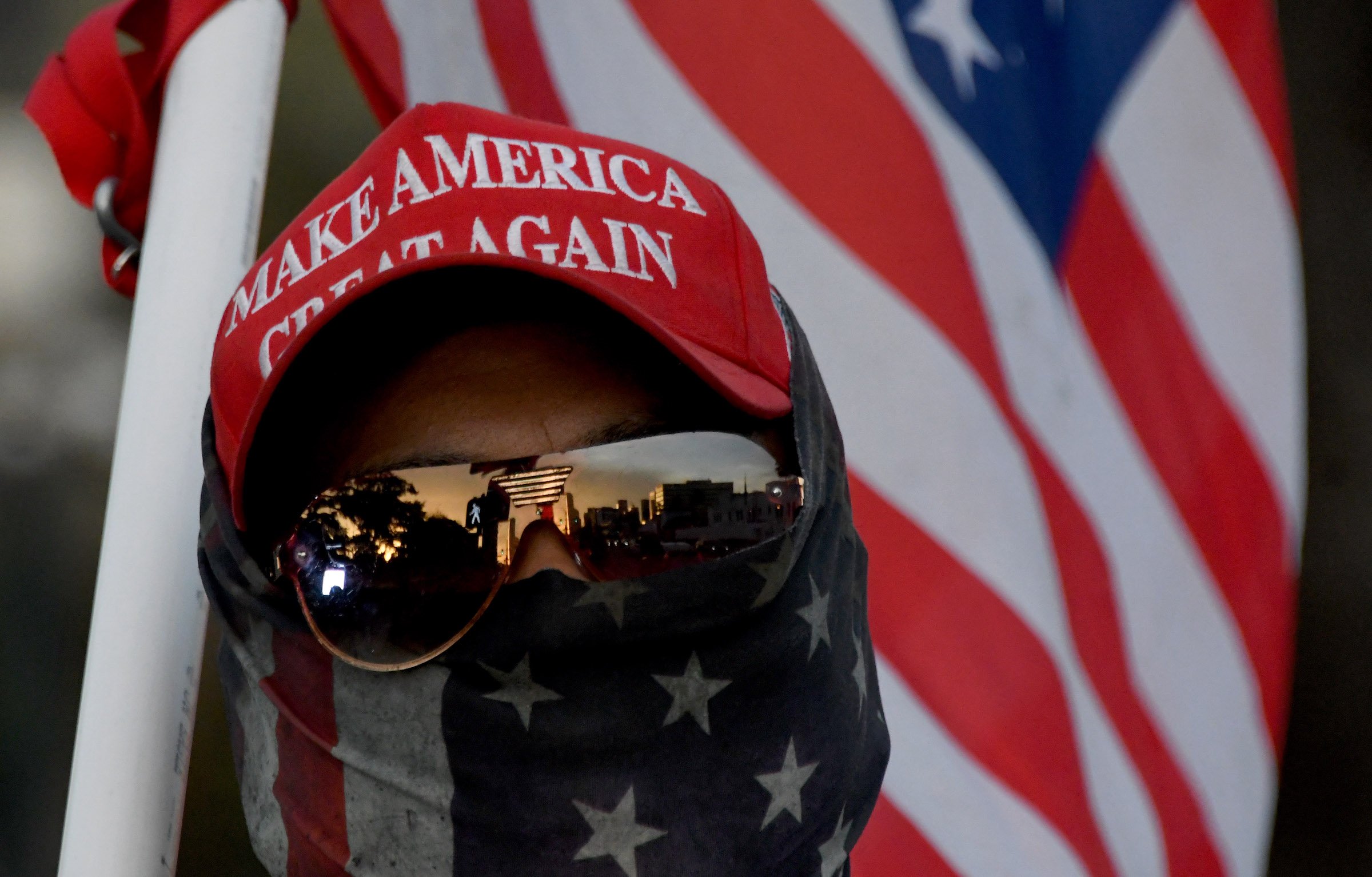 A man wearing a MAGA hat and carrying a flag