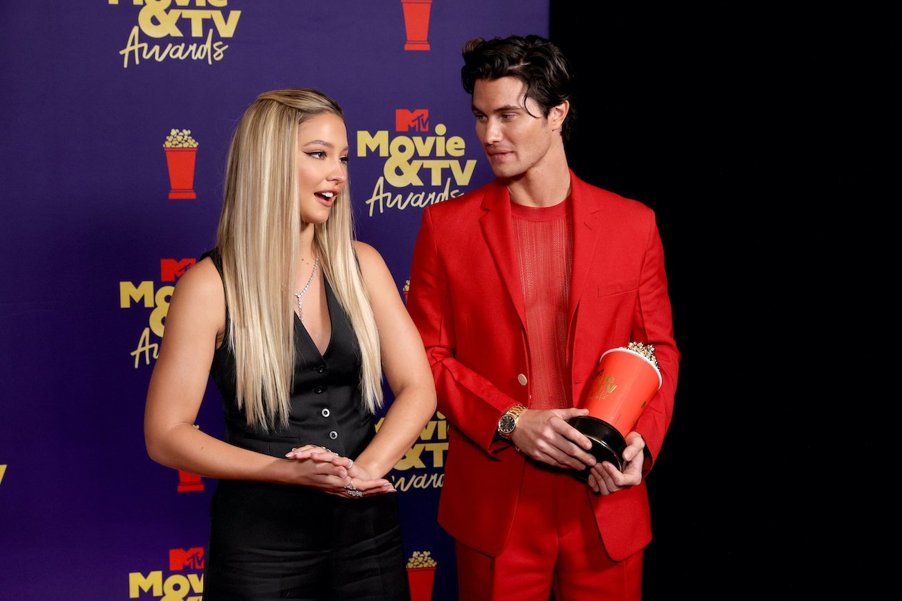 Fans speculate about Madelyn Cline and Chase Stokes in 'Outer Banks' Season 3, seen in this photo talking with press holding MTV's popcorn award
