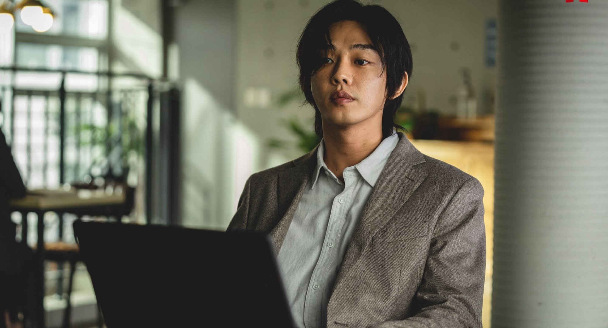 Character Jung Jin-soo from Netflix's 'Hellbound' sitting with laptop.