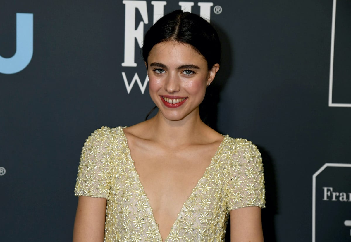 Margaret Qualley smiling in front of a black background