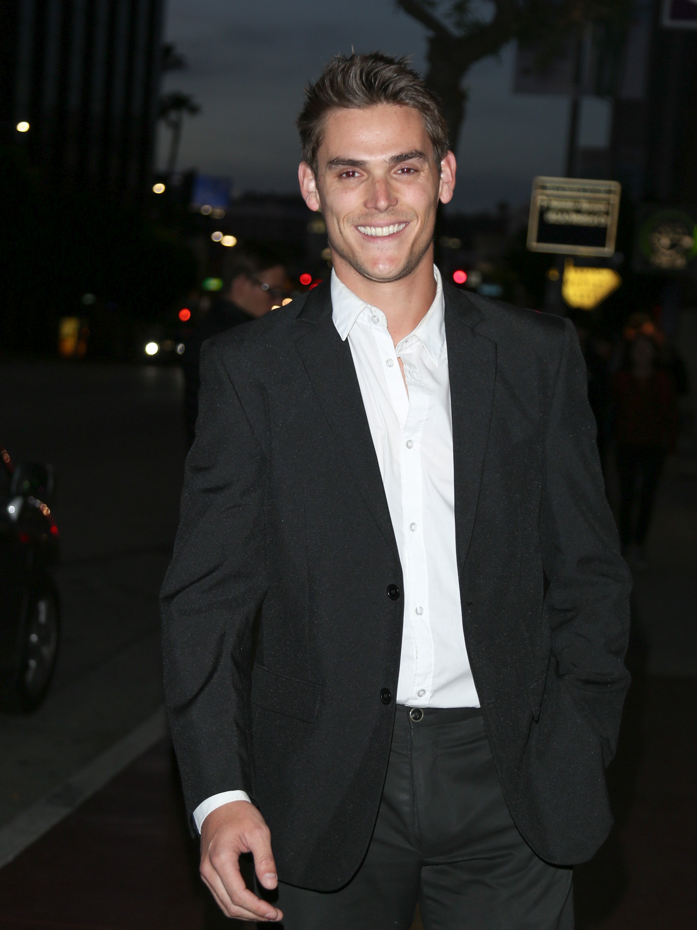 'The Young and the Restless' actor Mark Grossman wearing a black suit and white shirt; standing on a street.