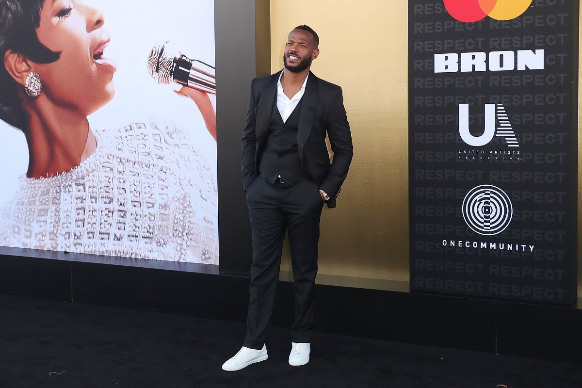 Marlon Wayans posing wearing black khakis and white sneakers