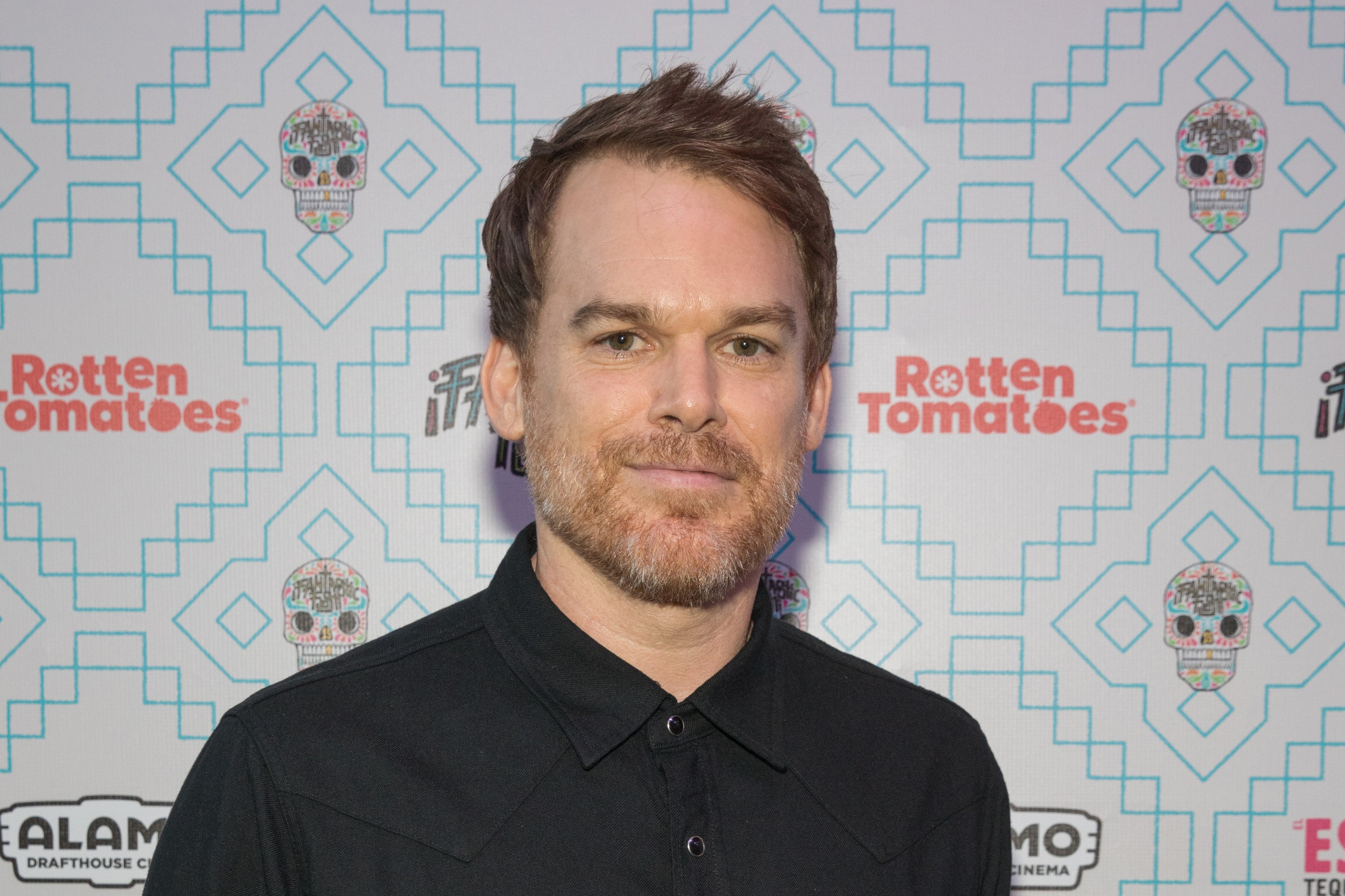 Dexter: New Blood star Michael C. Hall is wearing a black button-down shirt and has a mustache and beard.