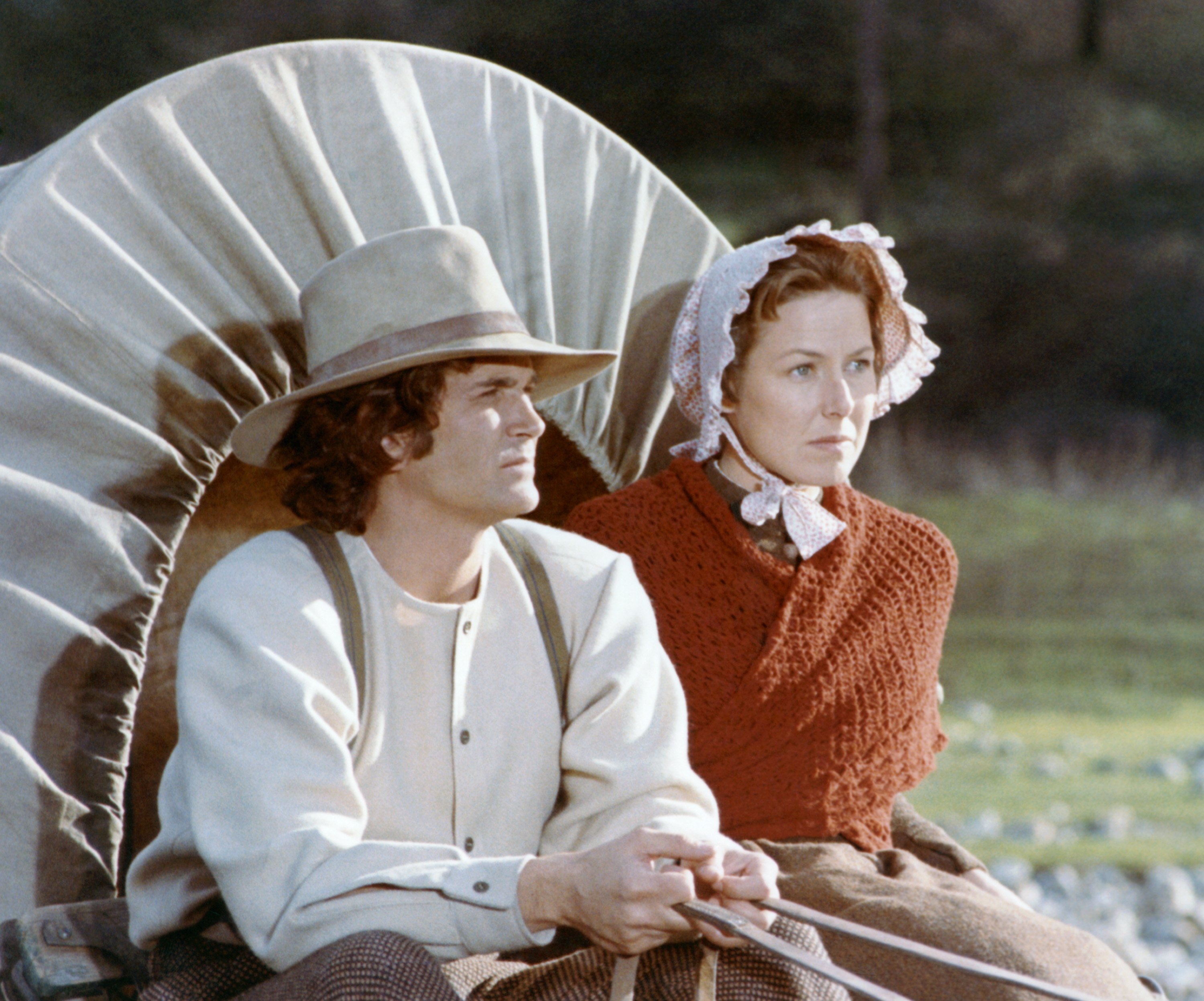 Michael Landon and Karen Grassle sit in a wagon during a scene from 'Little House on the Prairie'