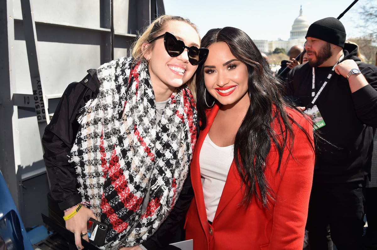 Miley Cyrus and Demi Lovato pose together at an event.