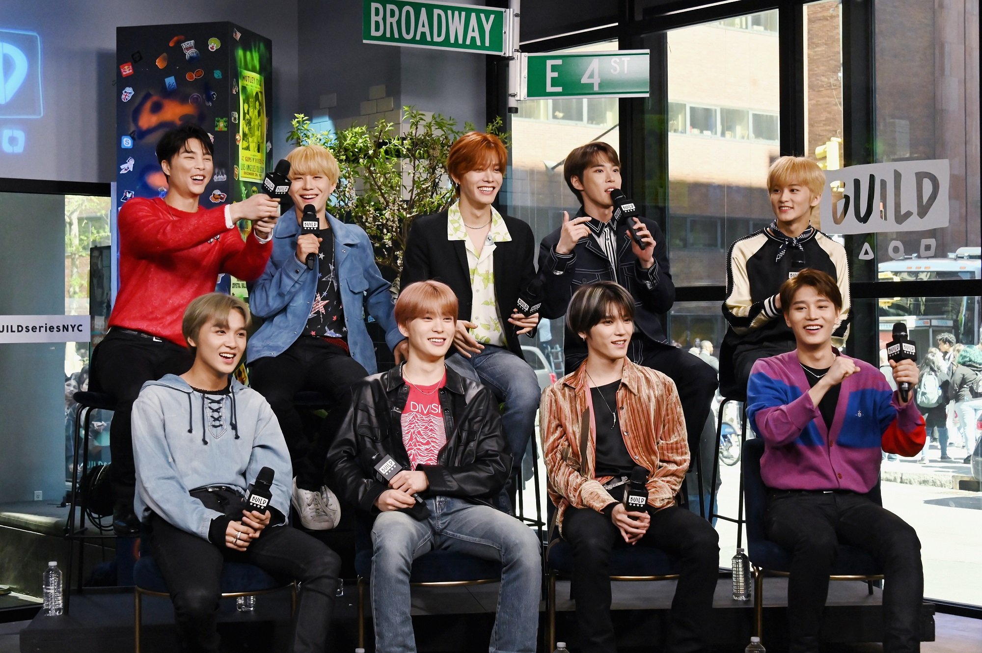 The members of NCT 127 sit in chairs at Build Series in 2019