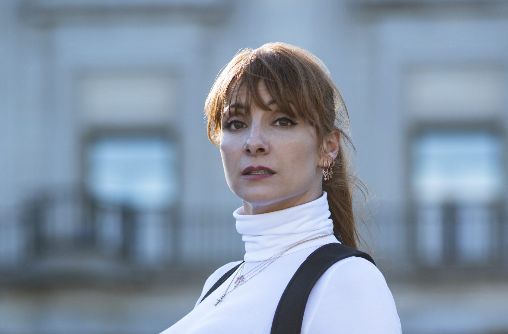 Najwa Nimri wearing a white turtleneck with black overalls in 'Money Heist.'
