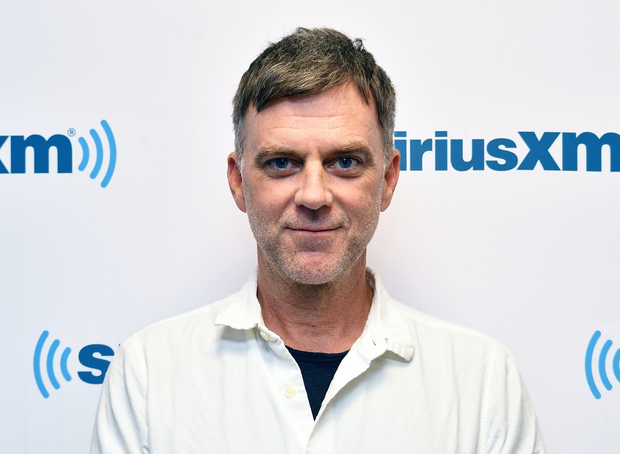 Paul Thomas Anderson image for article about 'Licorice Pizza' Asian gag with a white collared shirt in front of a step and repeat