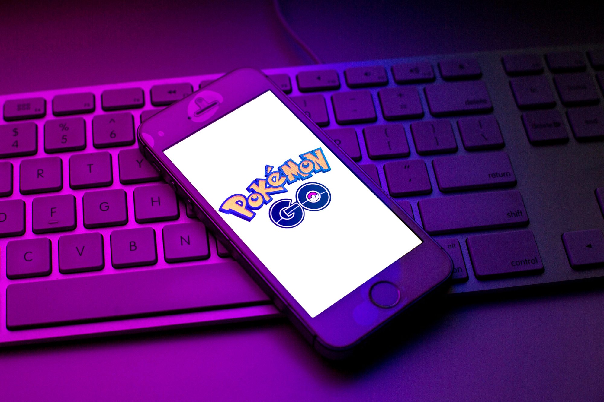 A phone with the 'Pokémon GO' app open on-screen. It's sitting on a keyboard and the lighting is purple and blue. 'Pokémon GO' is celebrating Día de Muertos from Nov. 1-2