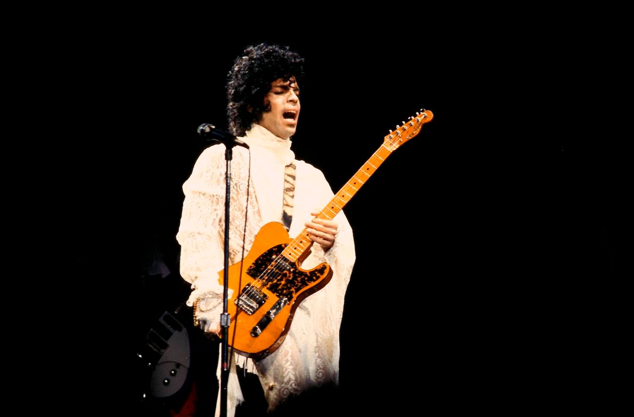 Prince wearing white while performing during his 'Purple Rain Tour' in 1984.