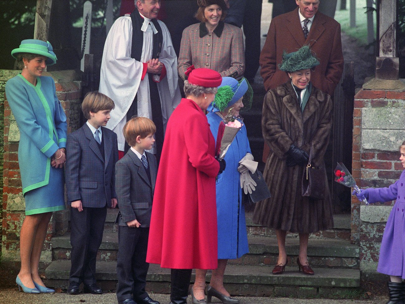 Princess Diana, Prince Harry, and Prince William stand near the Queen Mother as she accepts flowers