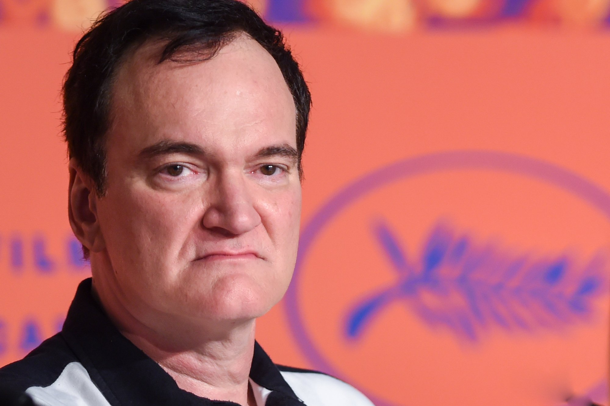 Quentin Tarantino at the 'Once Upon a Time in Hollywood' press conference looking serious with the Cannes logo behind him