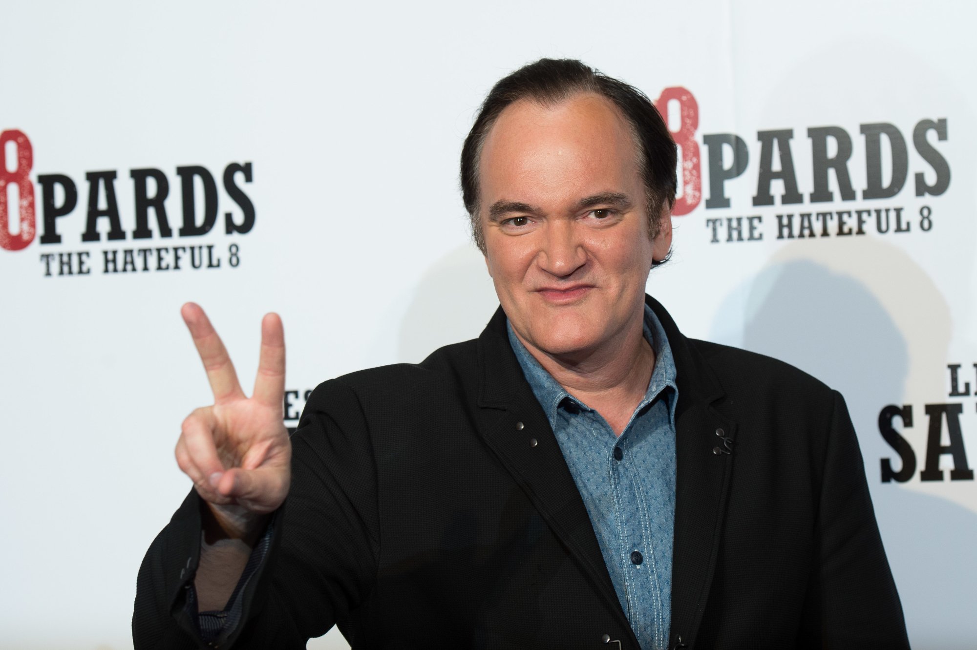 Quentin Tarantino films in order holding up a peace sign