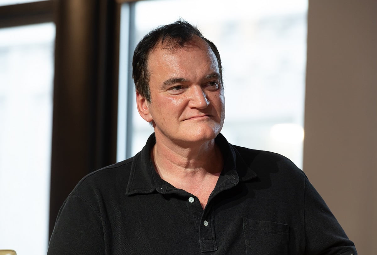Quentin Tarantino sitting down while wearing a black button up shirt