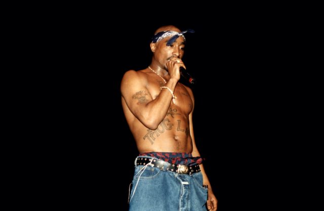 Rapper Tupac Shakur performing on stage in front of a black background