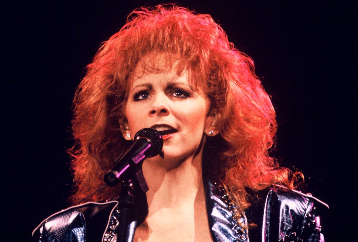 Reba McEntire sings into a microphone, circa 1993