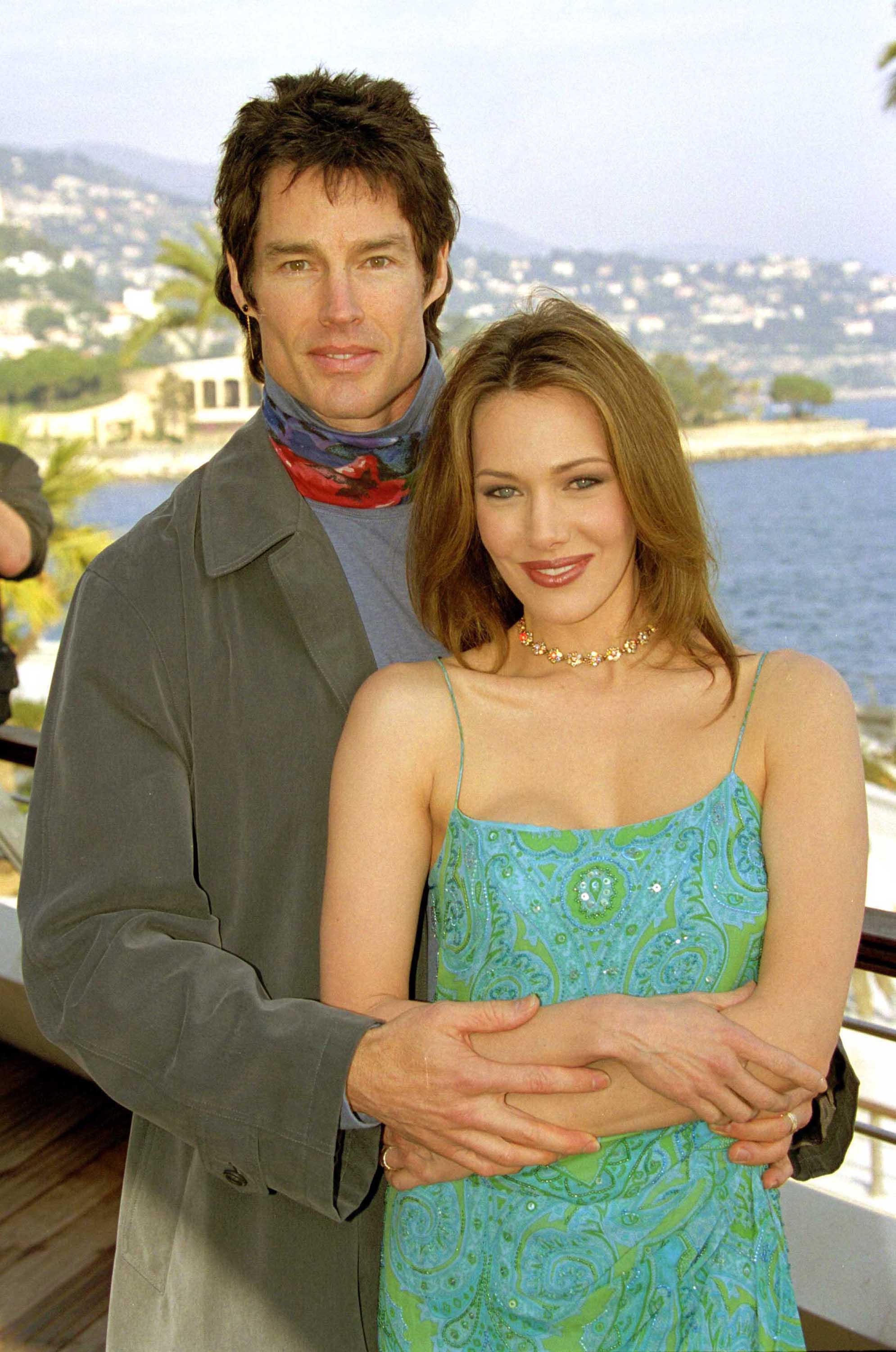 'The Bold and the Beautiful' actor Ronn Moss in a grey jacket and blue shirt, and Hunter Tylo in a blue dress, embrace for a photo.