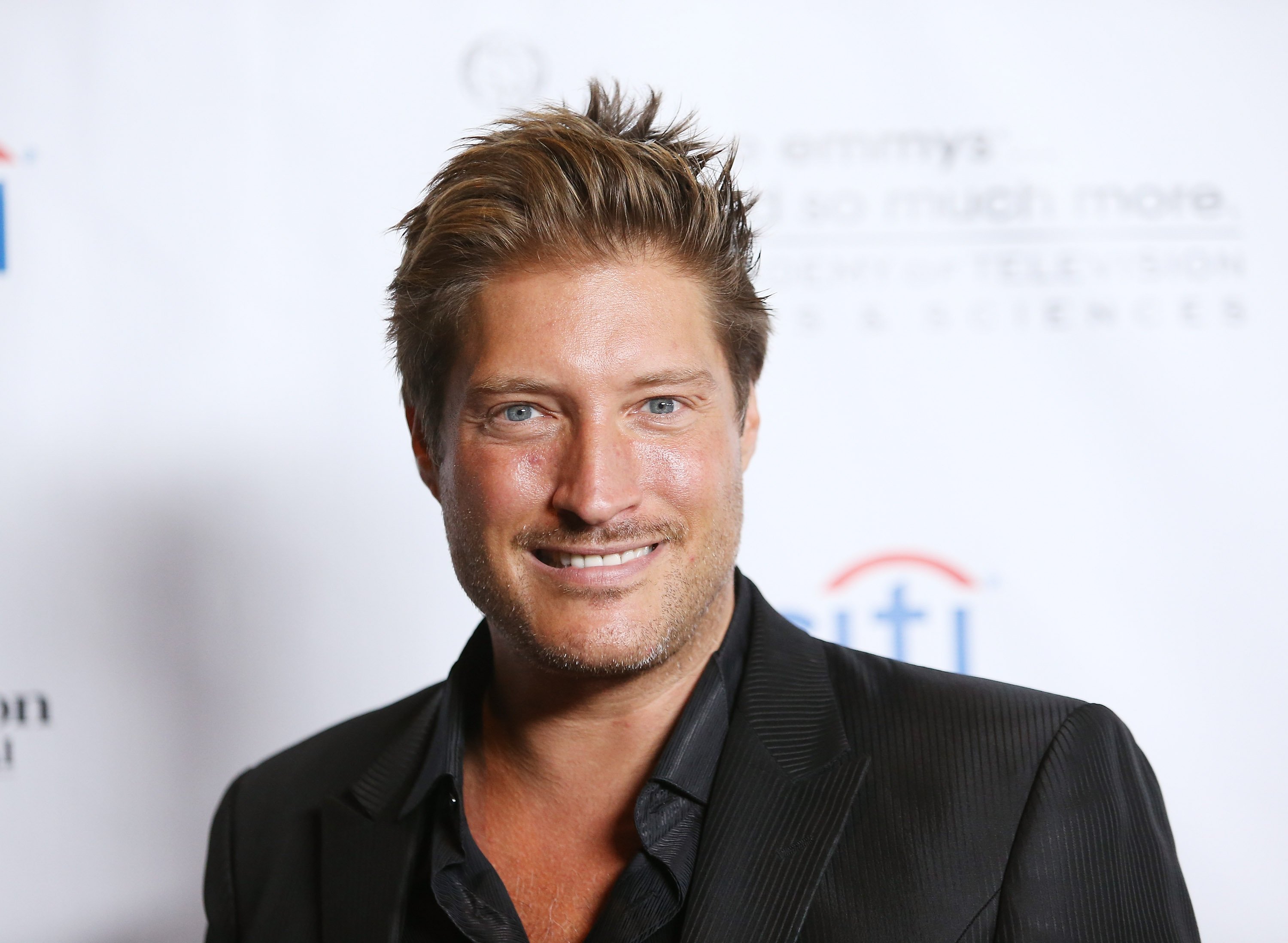 'The Bold and the Beautiful' actor Sean Kanan wearing a black shirt and suit, smiling for the camera.