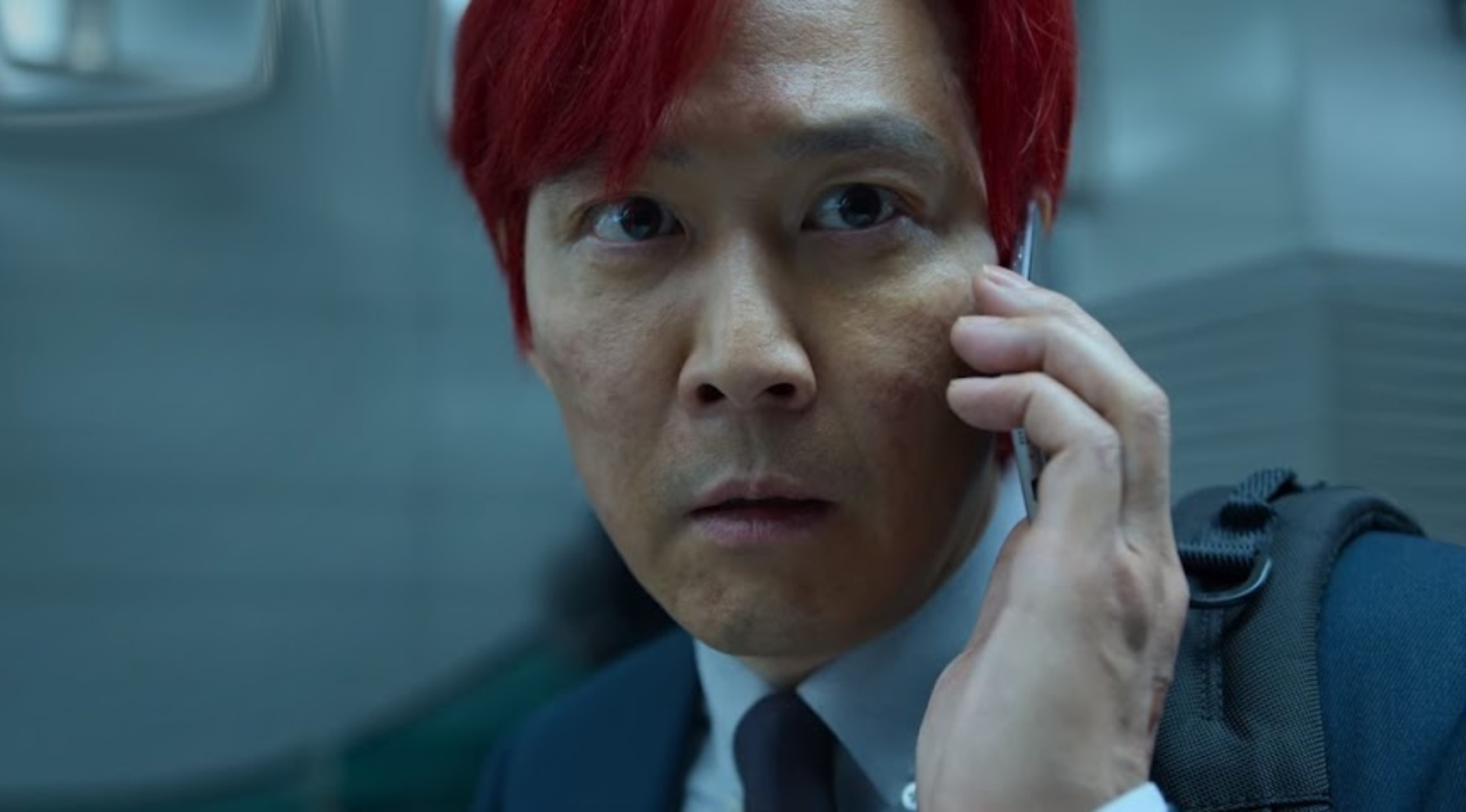 Seong Gi-hun character in 'Squid Game' ending scene talking on the phone with red hair.