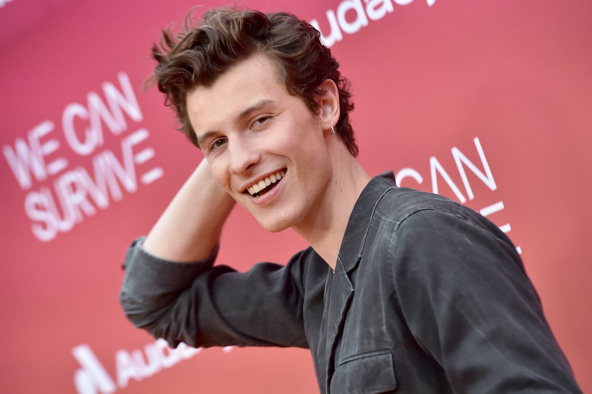 Shawn Mendes pushes his hair back and smiles for the camera.