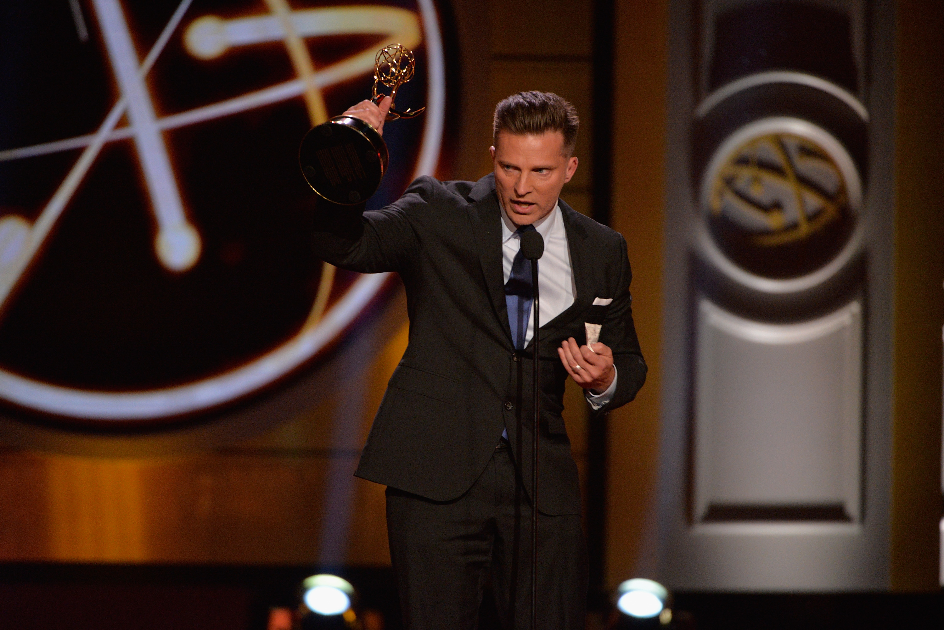 'The Young and the Restless' actor Steve Burton wearing a black suit and holding a Daytime Emmy Award.