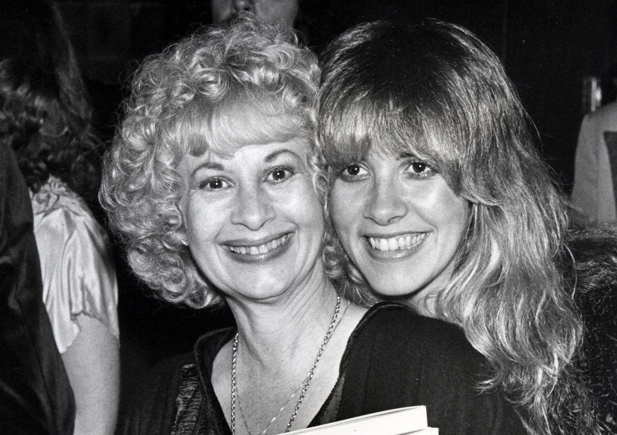 A black and white photo of Stevie Nicks and her mother Barbara Nicks. They both wear black and pose cheek to cheek.