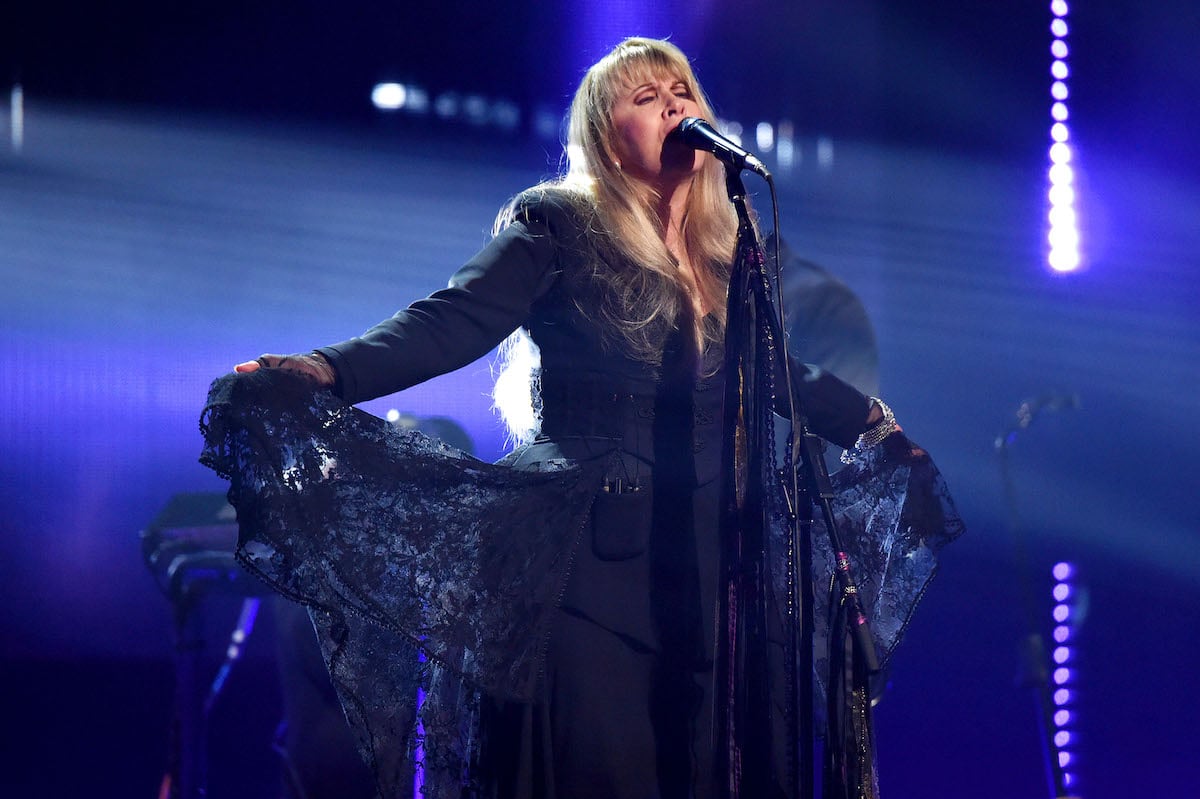 Stevie Nicks sings into a microphone on stage.